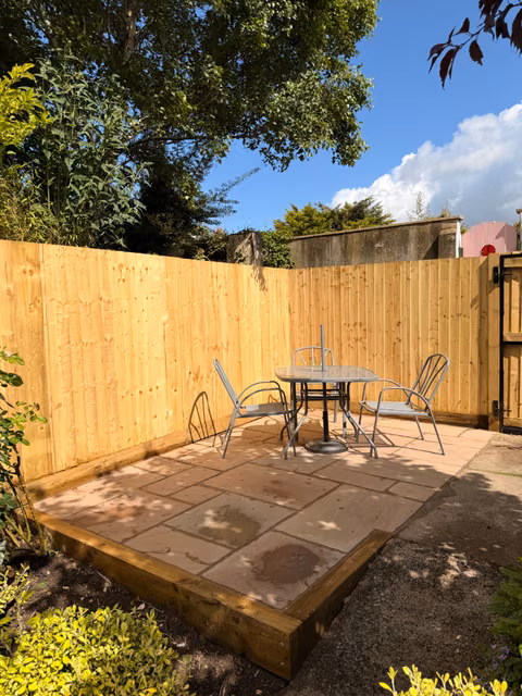 Completed sandstone patio with feather-edge fencing, sleeper retaining wall and garden gate in Brislington