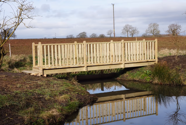 Bespoke timber footbridge with balustrades crossing a stream