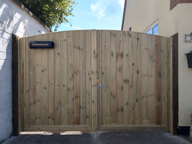 Pair of curved timber driveway gates made to fit between two walls