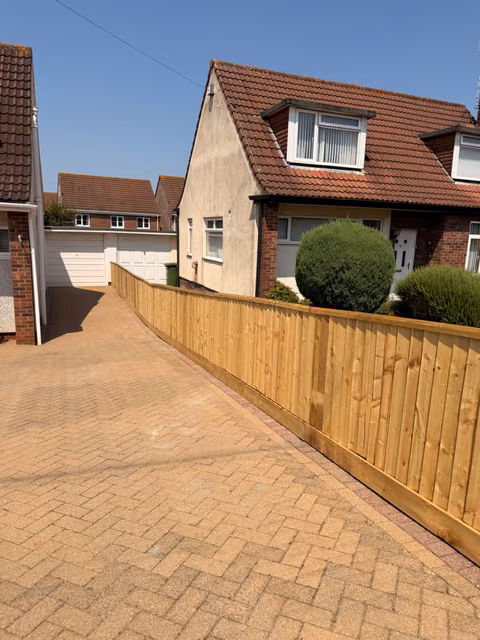 Feather-edge fencing following a sloping driveway with slim DuraPost supports in Emersons Green