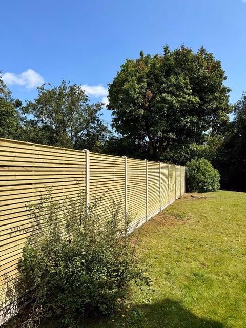 Long run of double-sided contemporary timber fencing with concrete posts and gravel boards